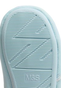 Lichtblauwe slipperzool met een getextureerd zigzag grippatroon en het "M&S" logo dat is gedrukt nabij het hielgebied.