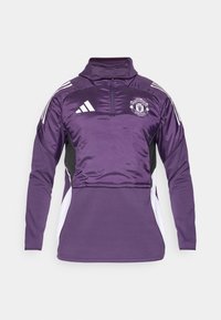 Lilla half-zip pullover med shiny stof, sorte sidepaneler, hvide accenter og Manchester United-logo på brystet. Blød tekstur.