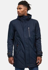 Veste parka marine avec capuche, fermeture éclair à l'avant, poches latérales et poignets élastiques. Fabriquée en matière lisse et résistante à l'eau.