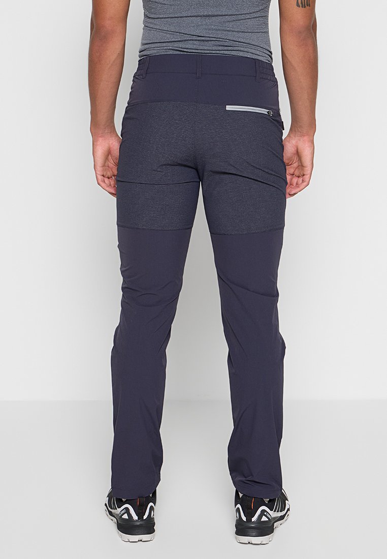 Pantalones de senderismo de color navy con paneles texturizados contrastantes, corte ajustado, bolsillo trasero con cremallera y costuras reforzadas; combinados con calzado en blanco y negro.