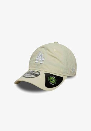 Cappellino da baseball beige con logo "LA" ricamato bianco, cinturino regolabile e visiera scura con branding New Era verde e nero sul lato.