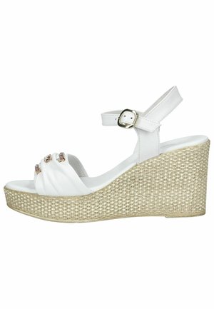 Witte sleehak sandaal met geweven platformzool, enkelbandje met gouden gesp en voorste bandjes versierd met edelsteenaccenten.