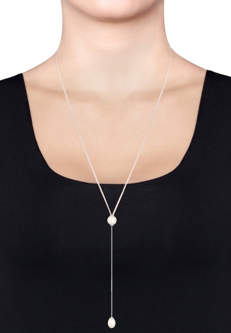 Zilveren hanger ketting met een Y-vormig ontwerp, met twee witte parels aan een dunne ketting. De achtergrond is zwart.