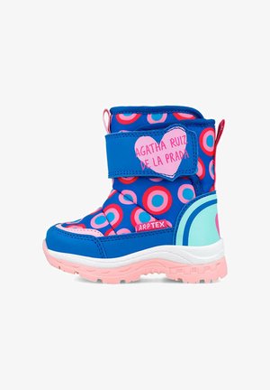 Bota azul impermeable con un patrón circular en rosa y azul, correa de Velcro, acentos rosas, suela de goma y detalles de logo en forma de corazón.