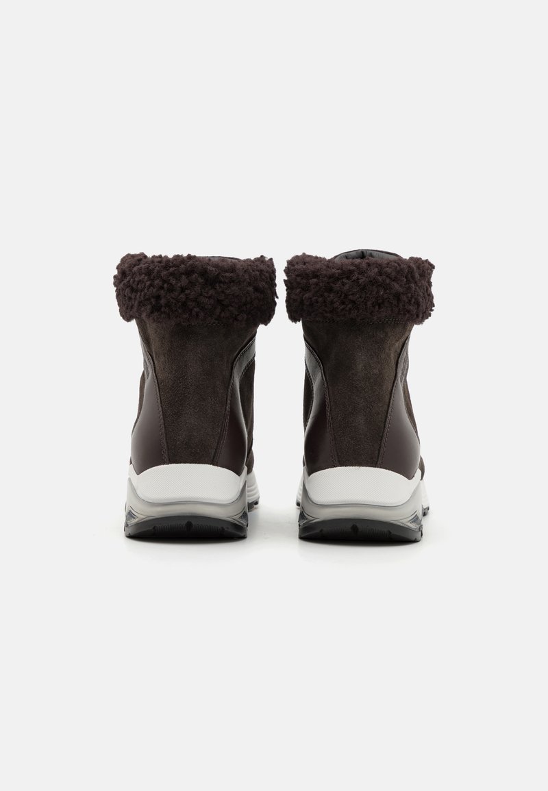 Botas tobilleras de ante marrón con un mullido puño marrón oscuro, que presentan una entresuela blanca y una suela exterior de goma negra, diseñadas para la comodidad y el soporte.