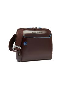 Bolso mensajero de cuero marrón con detalles en cremallera azul, herrajes plateados y una correa ajustable. Cuenta con un compartimento principal con cremallera y un bolsillo frontal.