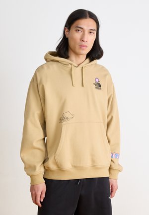 Felpa beige con cappuccio regolabile, tasca frontale e stampe grafiche, tra cui un'immagine di campeggio e testo colorato sulla manica.
