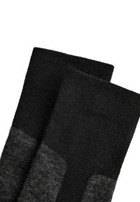 Svarta strumpor med en texturerad stickad design, med ett mörkare grått ribbat mönster i fotområdet för ökad kontrast och stöd.