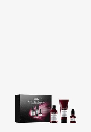 L'Oréal Vitamino Color Spectrum-set med tre burgundifärgade flaskor och en kräm, förpackad i en svart låda med färgglada kosmiska grafiska mönster.