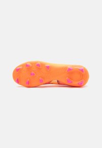 Suola di una scarpa sportiva arancione brillante con sei punte in gomma rosa, caratterizzata da motivi testurizzati e un design curvo per una maggiore aderenza.