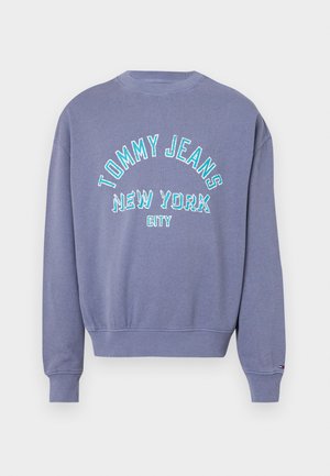 Lila környakú pulóver bordás mandzsettával és hemhel, elöl kék és fehér "Tommy Jeans New York City" felirattal.