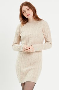 Robe pull en tricot beige à mailles torsadées avec des manches longues, des poignets côtelés et un col rond. Présente des détails de motif texturé sur l'ensemble.