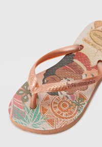 Rose gold flip-flop with textured straps, featuring a colorful printed footbed with tropical patterns and graphic designs.