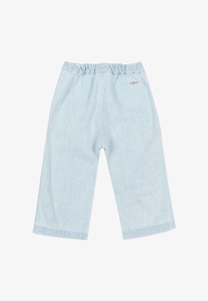 Pantalon large bleu clair, court, avec une ceinture élastique et un petit logo doré de la marque sur le devant droit, en haut.
