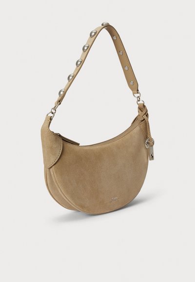 Zamszowa torba na ramię w jasnobrązowym kolorze o zaokrąglonym kształcie, posiadająca paski z ćwiekami, zapinana na zamek oraz małą zawieszkę z logo.
