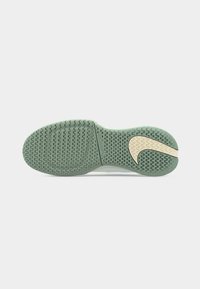Σόλα πράσινου και μπεζ παπουτσιού Nike με υφασμένο σχέδιο ζιγκ-ζαγκ και ορατό λογότυπο Nike swoosh στη φτέρνα.