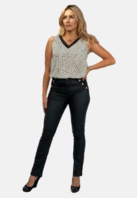 Czarnobiała w kratę bezrękawnik z koronkowym wykończeniem, połączony z dopasowanymi czarnymi spodniami z złotymi guzikami. Gładki materiał, dopasowany krój.