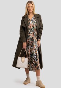 Oliivinvihreä trench-takki, kukkakuosiset mekko vaaleanpunaisena ja vihreänä, beige käsilaukku logolla, beige tennarit, teksturoitu kangas.