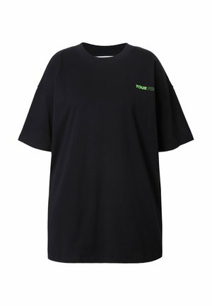 Zwarte oversized t-shirt van katoen, met korte mouwen en een ronde halslijn. "YOUR" is in het groen op de voorkant gedrukt.