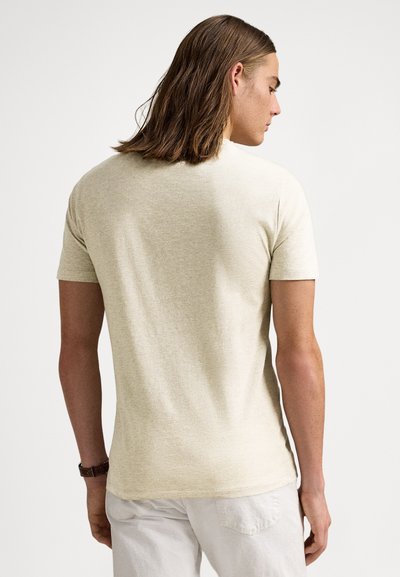 Světle béžové tričko s krátkým rukávem vyrobené z měkké, texturované látky. Má klasický kulatý výstřih a přiléhavý střih s minimálním vzorem.