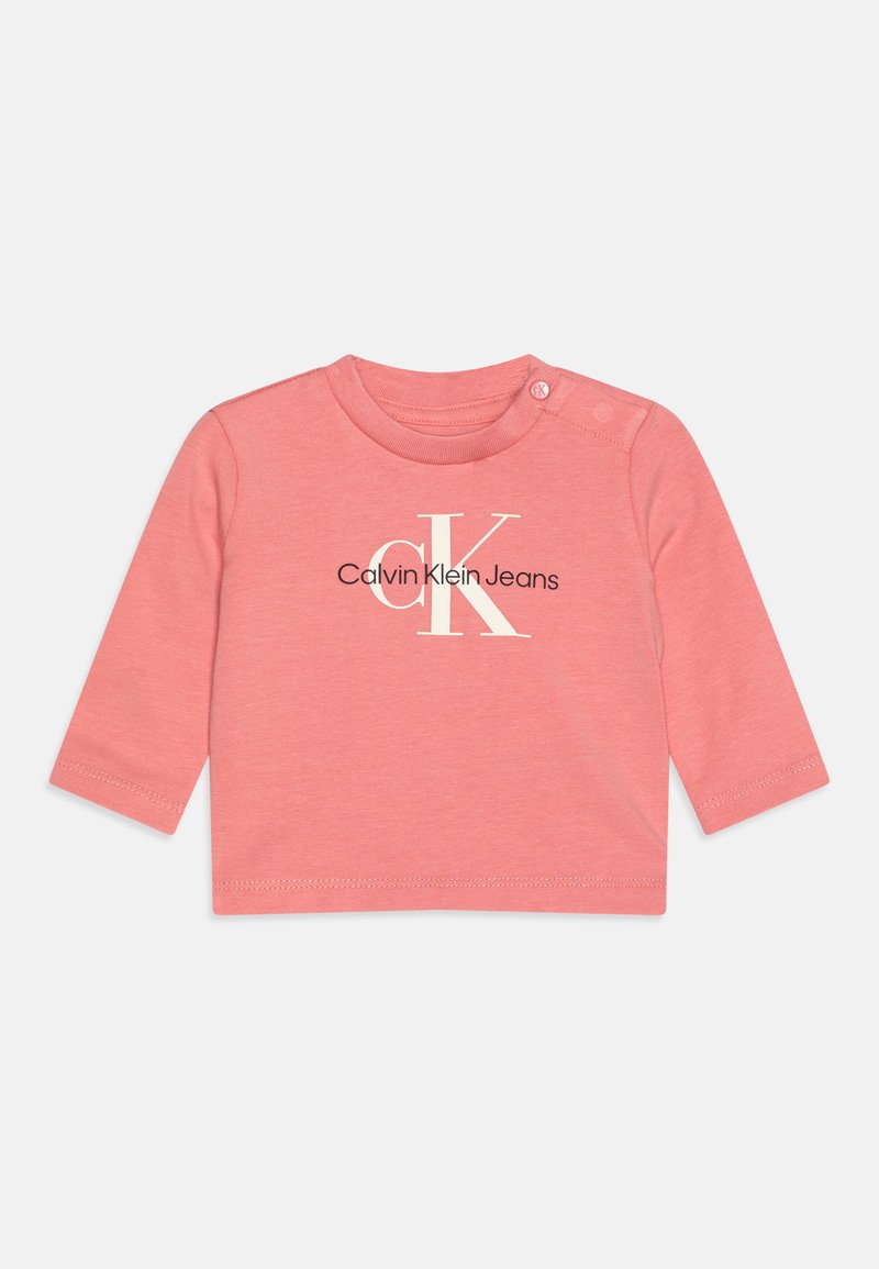 Roosa pikkade varrukatega beebipaita, mis on valmistatud pehmest puuvillast, ümar kaelus ja õlgadel nööbid. Ees on trükitud logo kujundus.