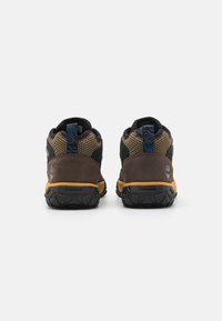 Hnědé a černé turistické boty s textilním svrchem, gumovou podrážkou, strukturovanými detaily a modrým akcentem na patě. Logo Timberland na boku.