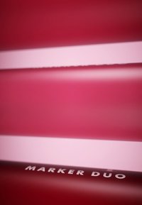 Pennarello rosso con finitura opaca liscia, caratterizzato da una striscia bianca e il testo "MARKER DUO" in lettere grassetto e prominenti.