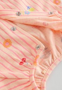 Pfirsichfarbener Stoff-Body mit pinken Streifen und bunten Blumen- und Schmetterlingsprints. Druckknopfverschlüsse am unteren Ende für einfaches Ankleiden.
