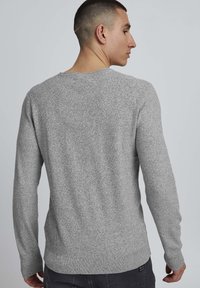 Pull en tricot gris avec un motif texturé, à manches longues et col rond. Doté d'un ourlet et de poignets côtelés. Vue de dos.