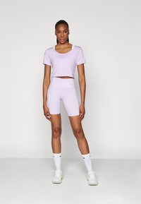 Fialová športová súprava z topu a šortiek s crop dizajnom, jemnou textíliou a decentným logom Nike. Zosilnená bočnými vreckami a priliehavým strihom.