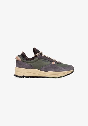 Zapatillas deportivas grises y verdes que presentan materiales de ante y malla, una media suela gruesa beige y una suela exterior texturizada negra con acentos naranjas.