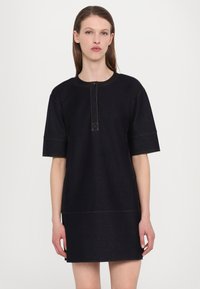 Robe en denim noire à manches courtes, décolleté rond, détail de boutons à l'avant et couture orange contrastante. Coupe droite et ajustée à la taille.