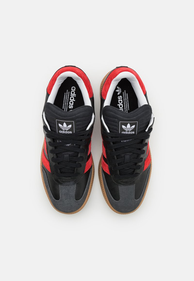 Czarno-czerwone sneakersy wykonane z zamszu i skóry, z gumową podeszwą, okrągłymi sznurowadłami oraz logo Adidas na języku.