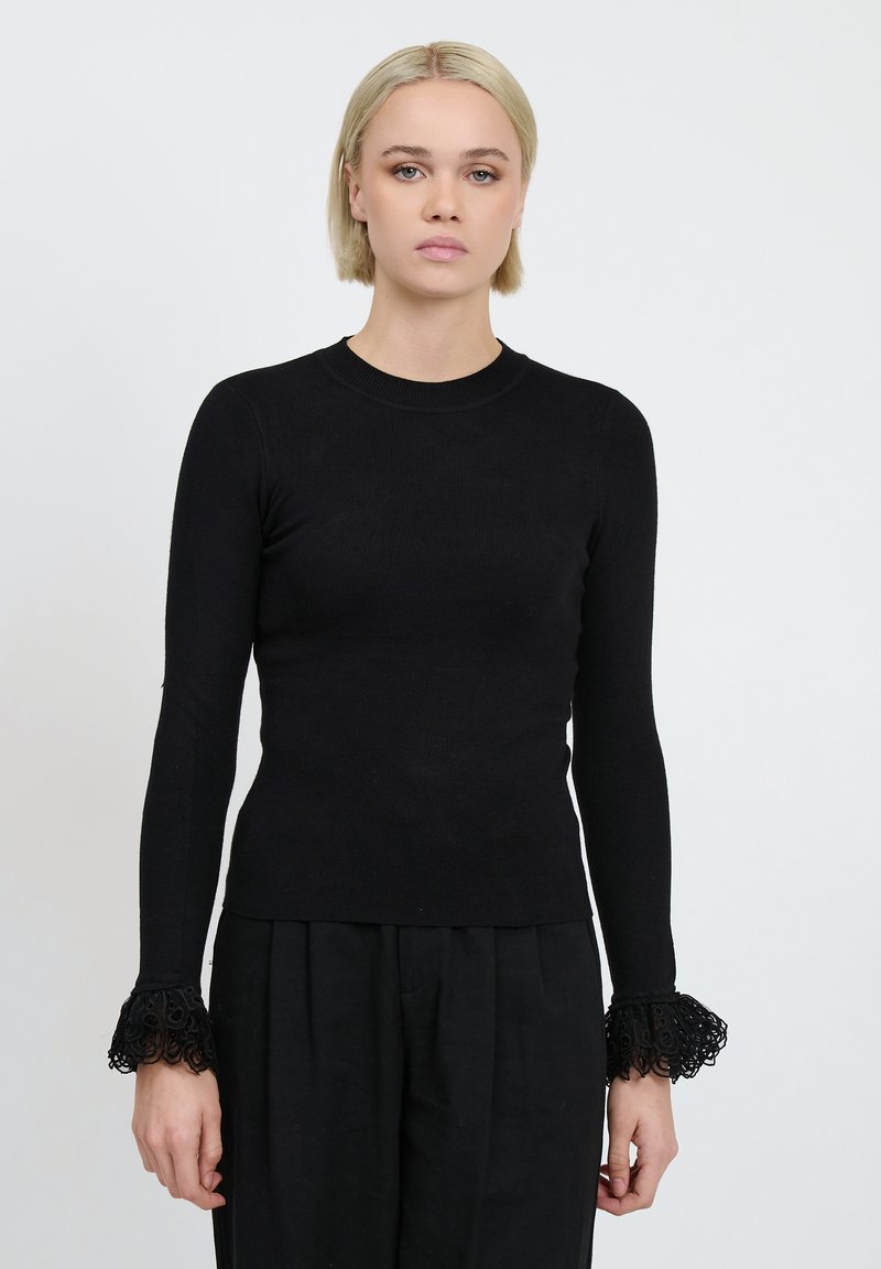 Top nero a maniche lunghe realizzato in tessuto a costine, con dettagli in pizzo intricate sulle maniche e scollo rotondo.