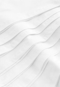 Weißer Textilstoff mit weichen, drapierten Falten. Subtile Nähte sorgen für akzentuierte Details, die eine glatte und fließende visuelle Ausstrahlung erzeugen.