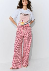 Gray T-shirt with pastel dessert graphic and "Café & Gâteau Paris" text. Red and white gingham wide-leg pants with an elastic drawstring waist.