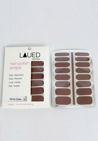 Nagellackfolien in verschiedenen Brauntönen sind in einem transparenten Plastiktablett neben einer Pappverpackung mit der Aufschrift "Mocha Shake" ausgestellt.