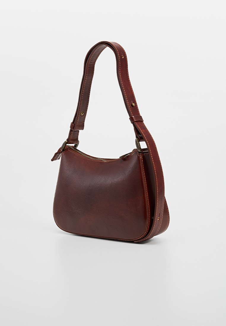 Braune Lederhandtasche mit geschwungener Form, verstellbarem Tragegurt und goldfarbenen Beschlägen. Glatte Textur und minimalistisches Design.