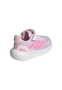 Zapatilla deportiva en color púrpura y rosa con parte superior de malla, correa con gancho y lazo, y suela texturizada blanca. Presenta tres rayas rosas en el lateral.