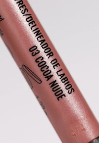 Crayon à lèvres dans un tube rose glossy et doux, avec du texte noir. L'étiquette indique "03 Cocoa Nude", avec un design minimaliste.