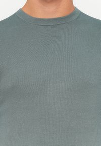 Light blue, ribbed crew-neck sweater made from soft fabric. Close-fitting design, featuring a smooth texture and minimal detailing.