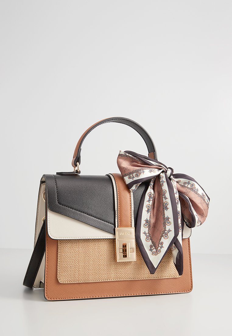 Sac à main en cuir avec des panneaux noirs, beige et crème, présentant une texture tissée, des accessoires en or, et une écharpe à motifs nouée sur la poignée.