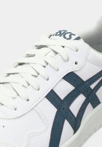 Valged spordijalatsid, millel on tekstuuriga nahast ülemine osa, sinised aktsendid ja lame pael. Omab brändimist keeles ja külgedel kontrastsetes värvides.