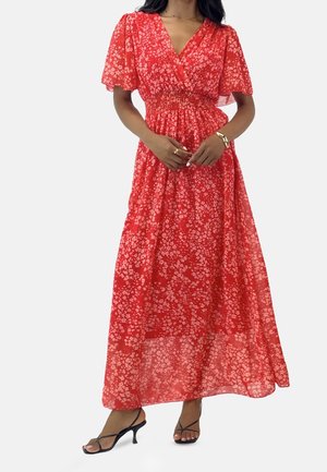 Punainen kukallinen maksimekko kevyestä kankaasta, jossa on lyhyet, pussihihat, smokkauksella korostettu vyötärö ja laskeutuva helma. Mustat remmikorkokengät.