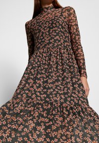 Langärmliges Kleid aus lichtdurchlässigem schwarzem Stoff mit einem Blumenmuster in Pink und Orange, mit hohem Kragen und gestuftem Rüschensaum.