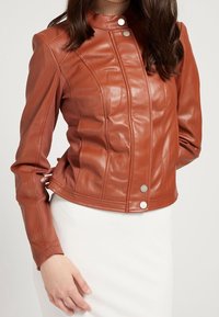 Veste en cuir marron au design ajusté, avec un col montant, des boutons-pression argentés et des détails de coutures verticales.