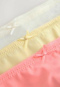Set di tre mutandine in bianco, giallo e rosa. Ognuna presenta un piccolo fiocco decorativo e una vita testurizzata con cuciture decorative.