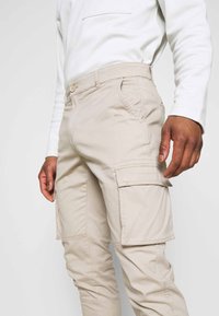 Beige cargobroek van katoenmix, met zijzakken, een knoopsluiting en een taps toelopend ontwerp voor een eigentijdse pasvorm.