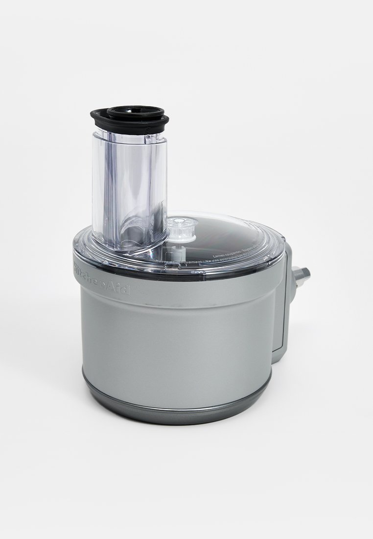 Appareil de cuisine, corps en plastique gris, dessus transparent, forme cylindrique, tube d'alimentation, base ronde, texture lisse, couvercle avec une petite ouverture.