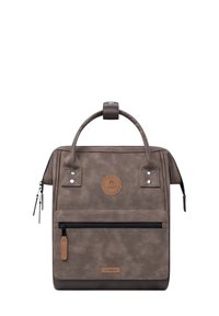 Braune Textiltasche mit strukturiertem Obermaterial, doppelten Griffen, einer vorderen Reißverschlusstasche und einem runden Logo-Patch auf der Vorderseite. Subtile Hardware-Akzente.